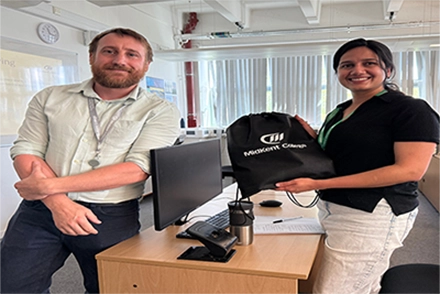 Apprentice Ayra (on the right) smiling whilst holding MidKent College bag